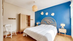 Une chambre à coucher comprenant un lit, une armoire, une chaise et une table de chevet avec une lampe.