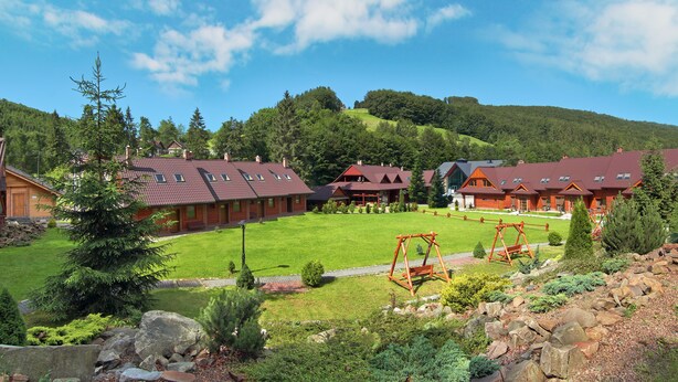 A resort with multiple wooden cabins, a well-maintained lawn, and a mountainous backdrop. - Dolina Leśnicy SKI & SPA Resort (Brenna)