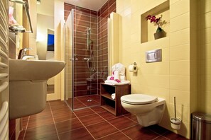 A bathroom with a shower, toilet, sink, and a small shelf with toiletries. - Dolina Leśnicy SKI & SPA Resort (Brenna)