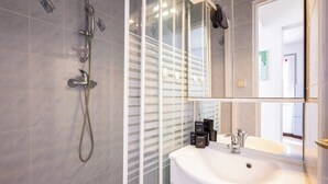 Une salle de bain moderne avec une douche à parois de verre, un lavabo blanc et un grand miroir.