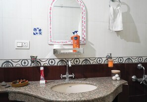 Ein Badezimmer mit einem Granitwaschbecken, einem Spiegel mit dekorativem Rahmen, einem Wandtuch und Pflegeartikeln auf der Ablagefläche.