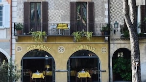 Un edificio con un ristorante chiamato "Ristorante del Battello", caratterizzato da una facciata in pietra, finestre ad arco e posti a sedere all'aperto.