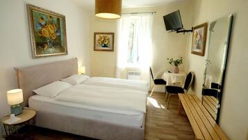 Une chambre d’hôtel avec un lit double, un bureau avec une chaise, une télévision et des œuvres d’art accrochées aux murs.