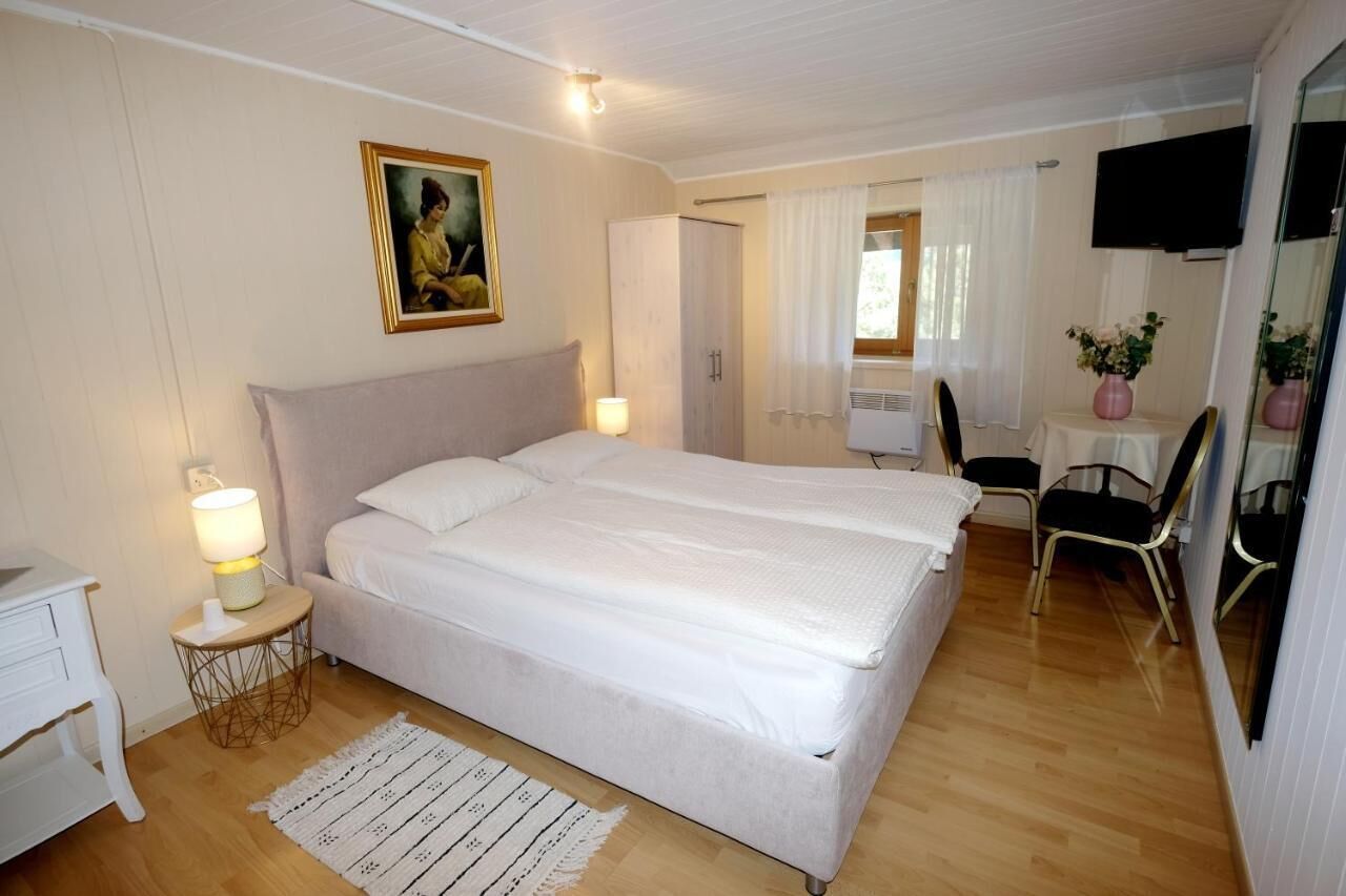 A bedroom with a large bed, bedside tables, a TV, and a painting on the wall.