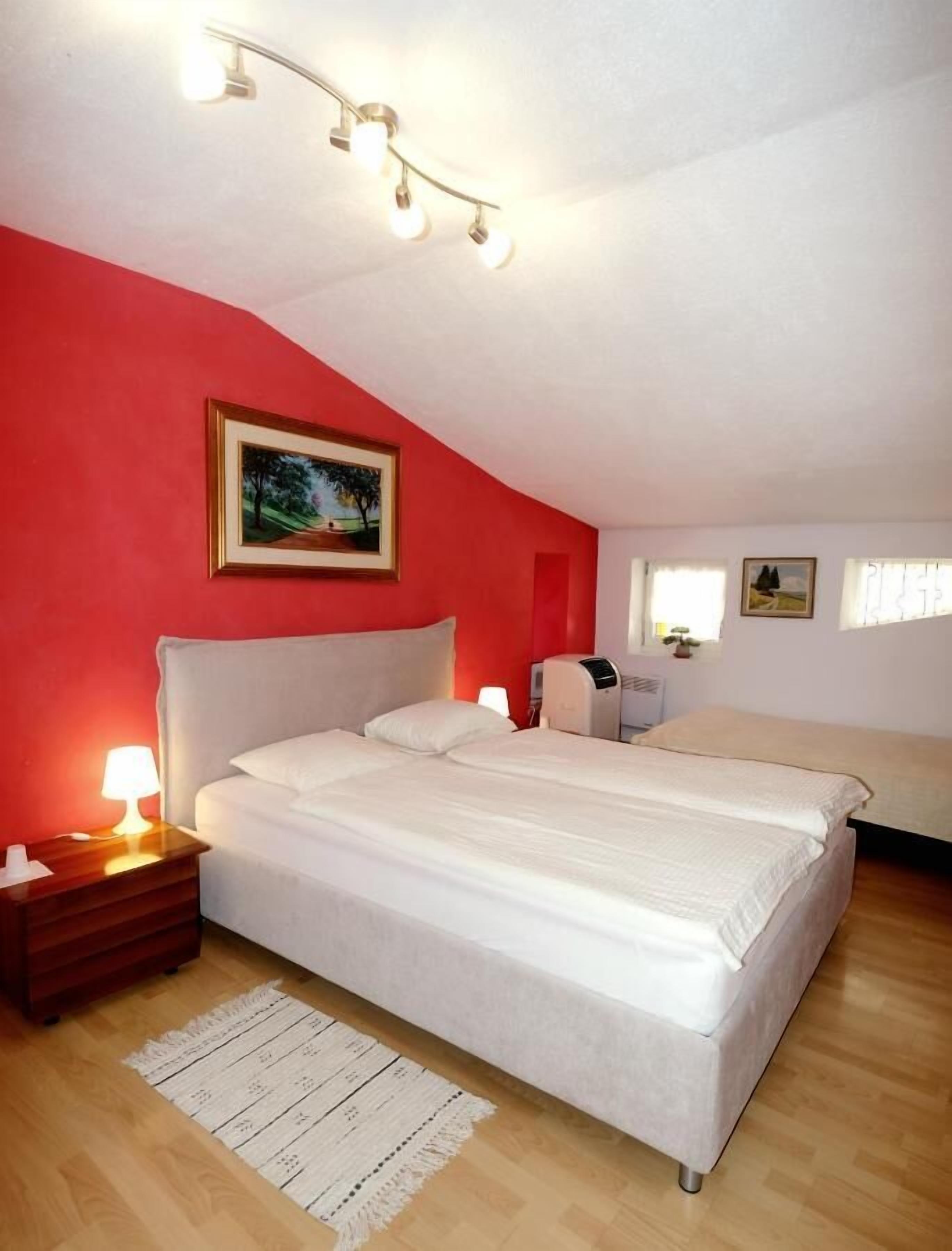 Une chambre avec un lit simple, une table de chevet avec une lampe, une commode et un luminaire fixé au mur.