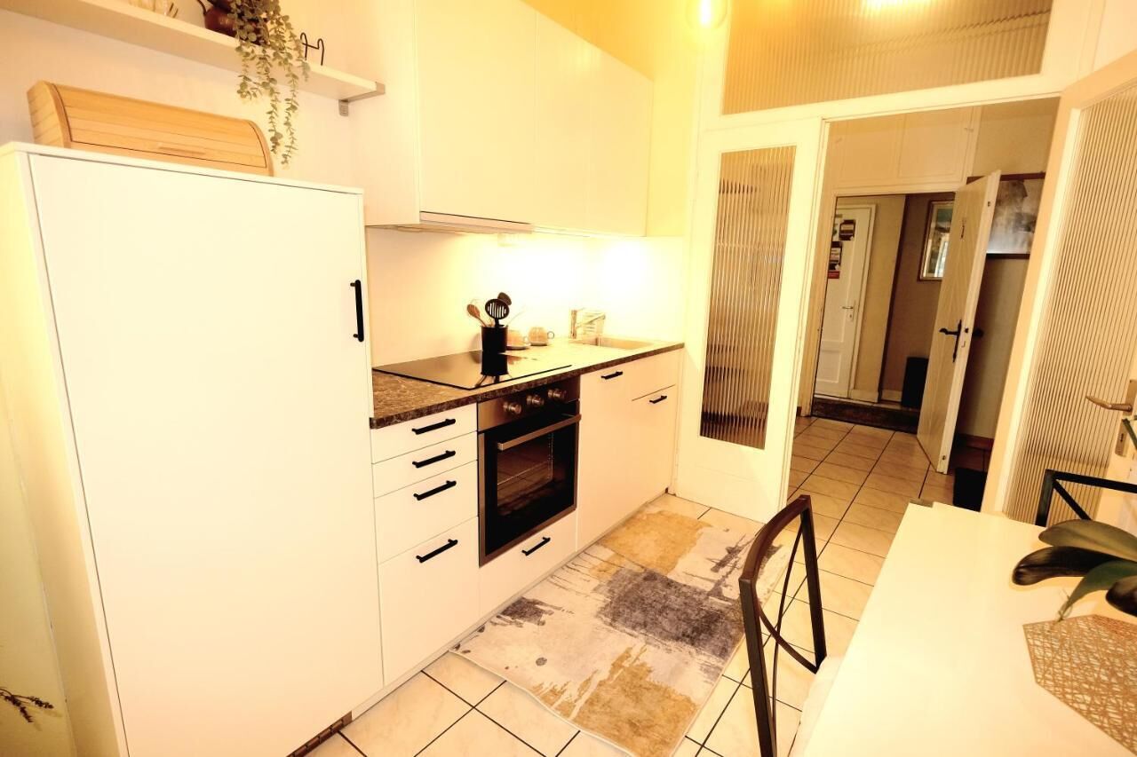 A compact kitchen with white cabinets, a built-in oven, and a countertop with kitchen utensils.