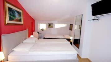 A hotel room with a large bed, a bedside table with a lamp, a TV mounted on the wall, and a painting on the wall.
