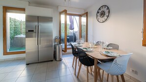 A dining area with a table set for four, a refrigerator, and a trash can. - LE PETIT SESAME L' évasions cosy jacuzzi terrace wifi parking 2 steps stadiumDF (Saint-Denis)