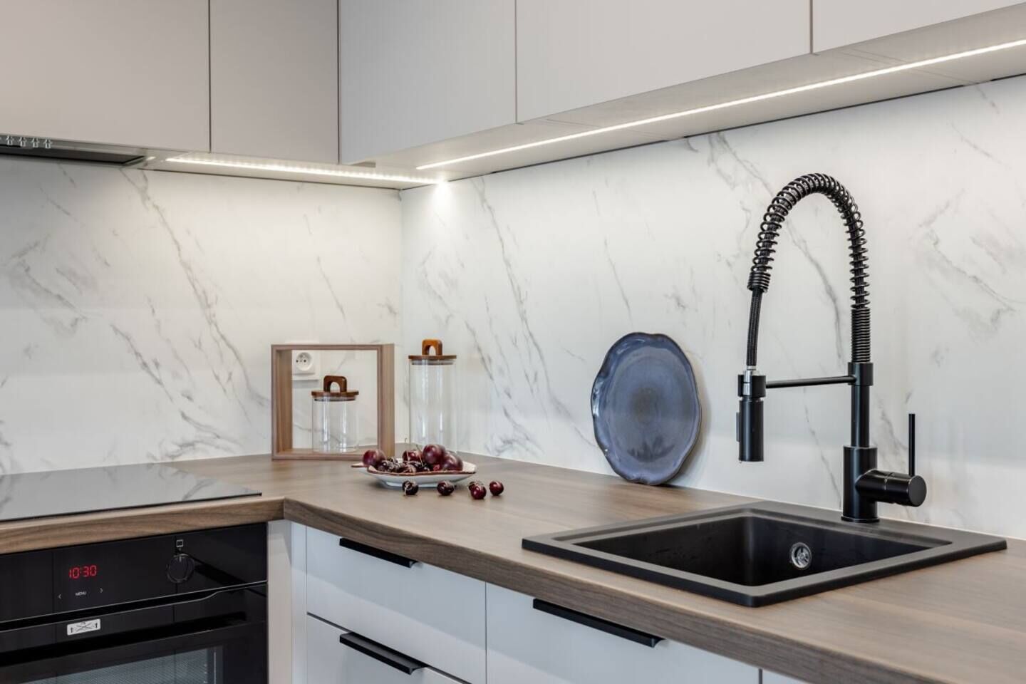 Una cocina moderna con un grifo negro, un salpicadero de mármol y una encimera de madera.