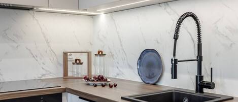 Una cocina moderna con un grifo negro, un salpicadero de mármol y una encimera de madera.