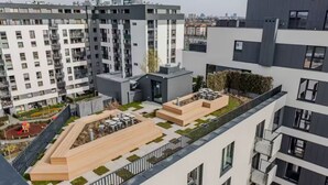 Ett modernt bostadskomplex med en takträdgård och ett utomhusområde med sittplatser.