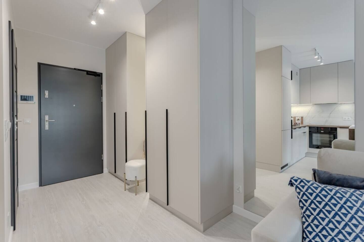 A modern interior with a neutral color palette, a minimalist design, and a visible kitchen area.