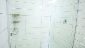 A glass-enclosed shower stall with white tiles, a glass door, and a white toilet visible to the right.