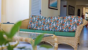 A wicker sofa with a patterned cushion in a well-lit room with tiled flooring. - Rota do Sol Praia Hotel (Guaratuba)