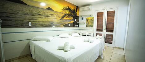 A hotel room with a bed, a bathroom, and a view of the sea.