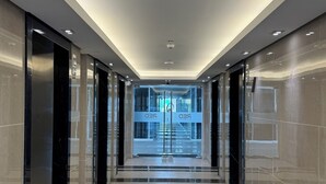 Un pasillo moderno con puertas de cristal, iluminación empotrada y suelo de baldosas.