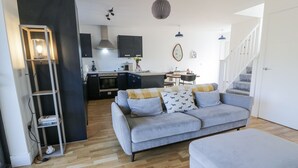 Un salon moderne avec un canapé gris, un plancher en bois et un escalier menant à un niveau supérieur.