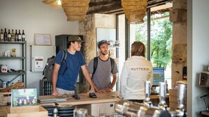 Eine Bar mit Theke, Gläsern und Flaschen. Menschen stehen dort und unterhalten sich.