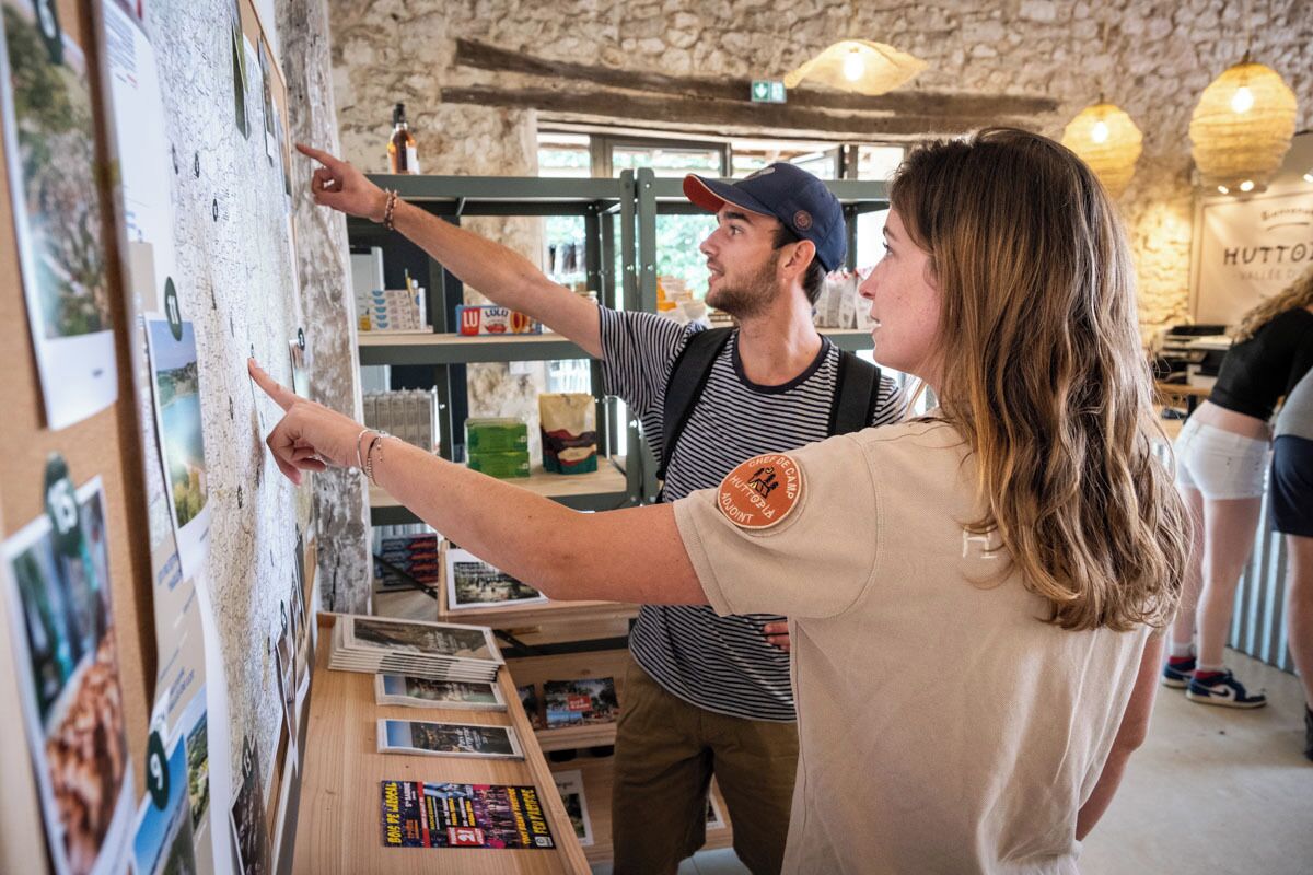 Eine Person zeigt auf eine Wand mit verschiedenen Fotos und Karten.