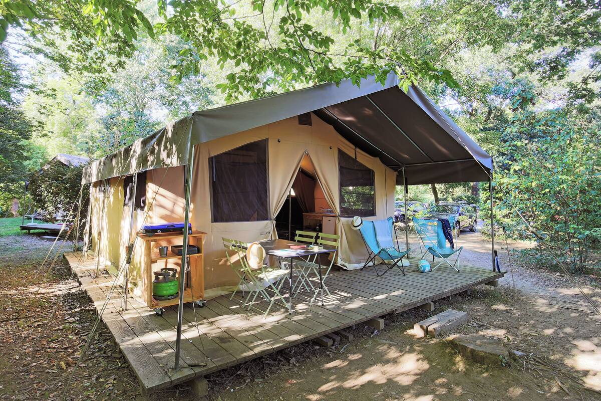 Un terrain de camping équipé d’une tente, d’une table, de chaises et d’une terrasse.