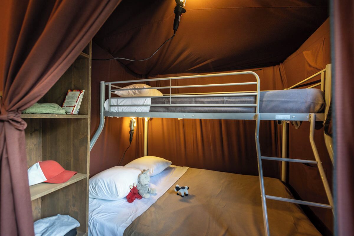 A bunk bed room with a shelf containing a book and a cap.