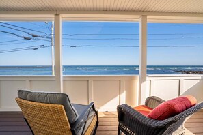 A covered outdoor seating area with wicker furniture and a view of the ocean. - Oceanfront Front Porch Back Deck Kitchen (Wells)