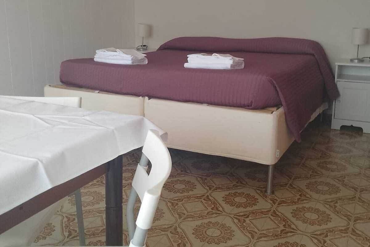 Una camera d'albergo con un letto, un tavolo e una sedia.