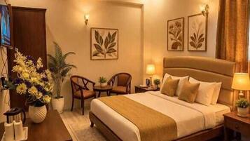 Una habitación de hotel con una cama grande, un escritorio, una silla, una mesita y una planta en maceta.