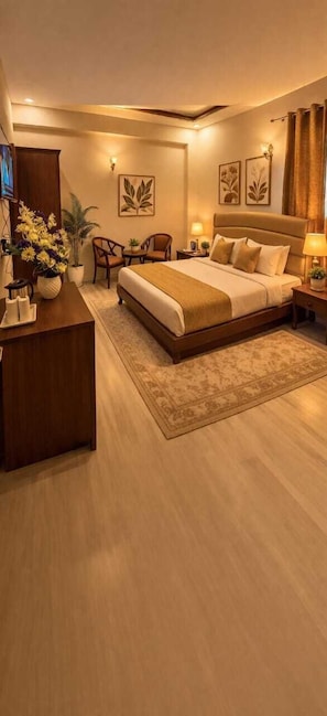 A hotel room with a large bed, a desk, a chair, a small table, and a potted plant.