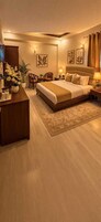 Una habitación de hotel con una cama grande, un escritorio, una silla, una mesita y una planta en maceta.