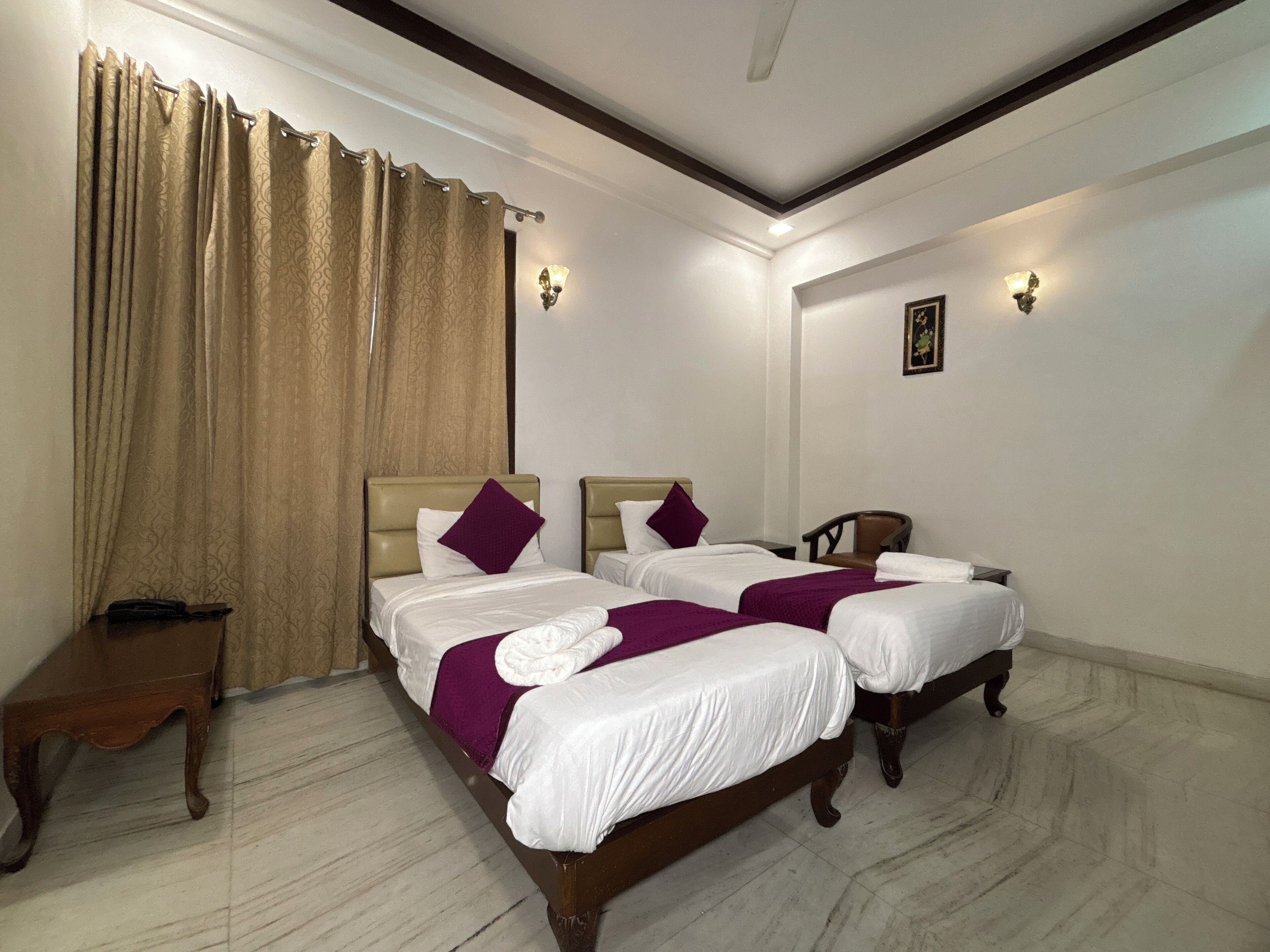 A hotel room with two beds, a wooden nightstand, a desk, and a chair.