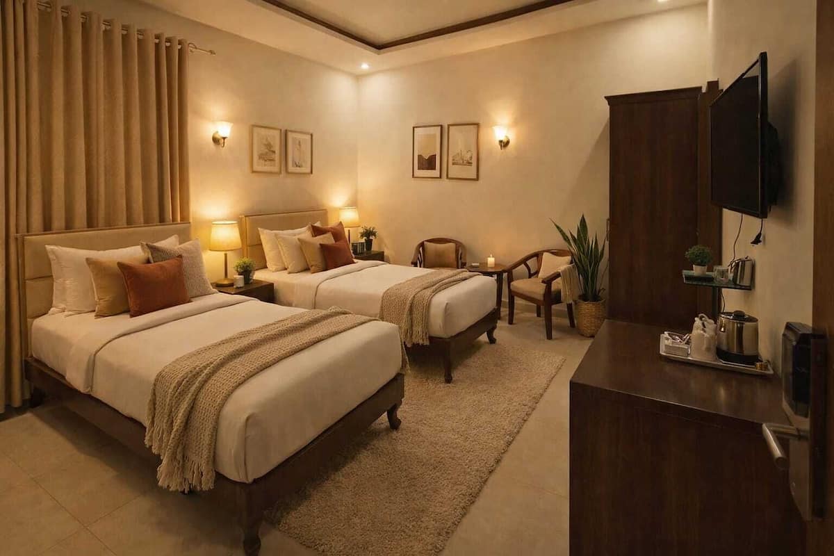 Habitación de hotel con dos camas, lámparas de noche, un escritorio con televisor, una silla y una planta.