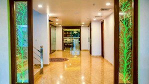A hotel lobby with a polished marble floor, wooden doors with frosted glass panels, and a staircase with a handrail. - Goyal Hoteliers - Hotel The Agra Grande (Agra)
