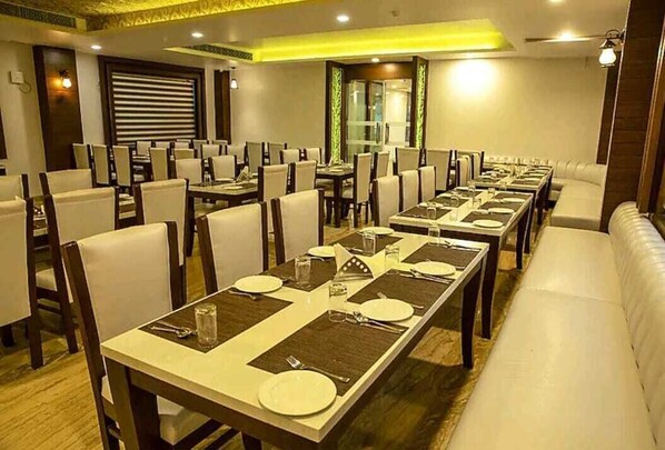 A hotel dining area with multiple tables set for dining, chairs, and a sofa.