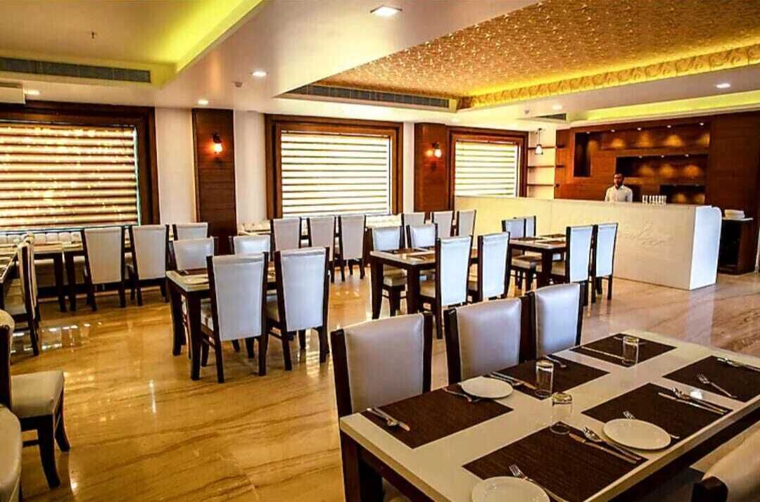 A restaurant with multiple tables and chairs, a reception area, and a ceiling with a textured design.
