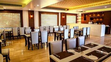 A restaurant with multiple tables and chairs, a reception area, and a ceiling with a textured design.