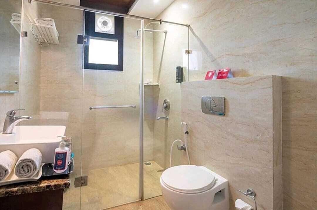 A modern bathroom with a glass shower enclosure, a toilet, and a sink with towels and toiletries.