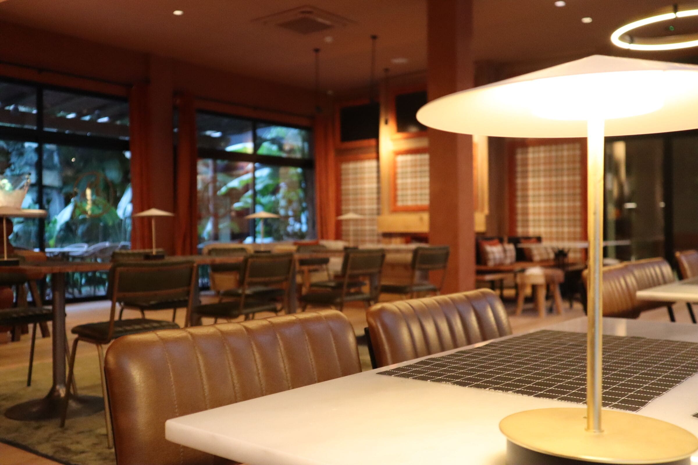 Interior de restaurante con mesas, sillas y una lámpara grande colgante.