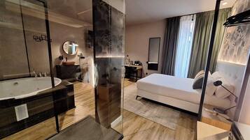 Una habitación de hotel moderna con una cama grande, baño independiente con bañera, escritorio y una silla.