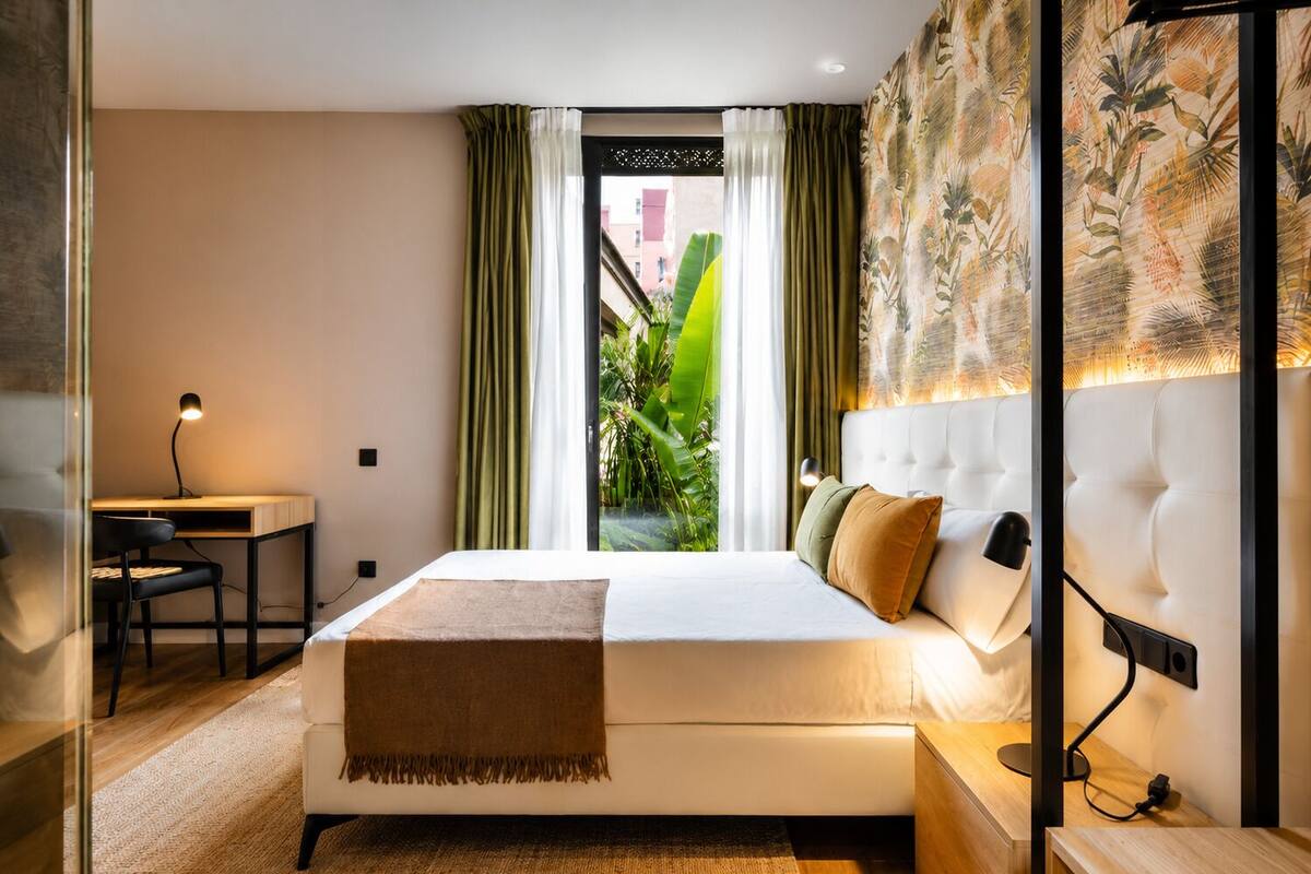 Una habitación de hotel moderna con cama, escritorio y vistas a zonas verdes.