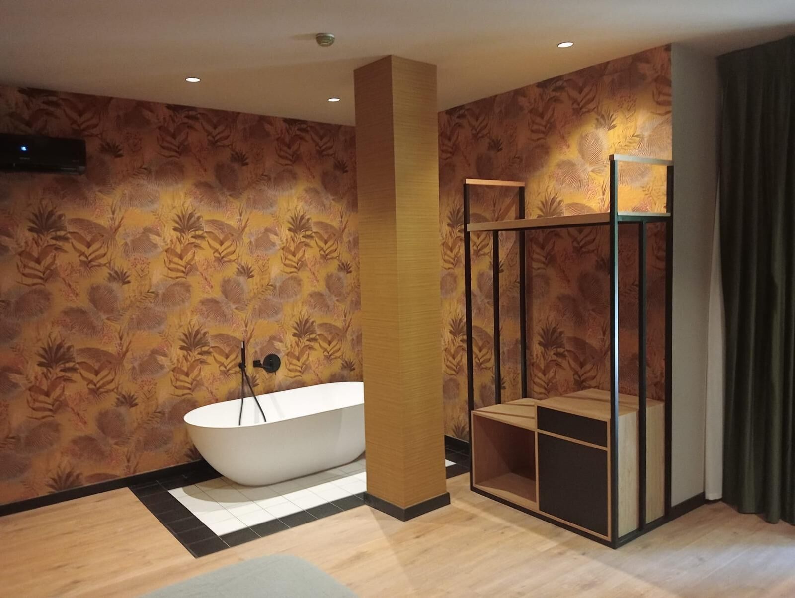 Un baño moderno con una bañera independiente, cabina de ducha con mampara de vidrio y papel pintado estampado.