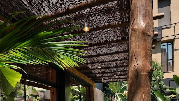 An outdoor patio with wicker furniture, a fire pit, and a thatched roof. - Saman Boutique Hotel (Valencia)