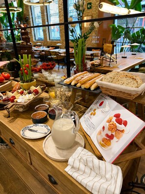 A buffet with various food items, a pitcher of milk, and a menu. - Saman Boutique Hotel (Valencia)