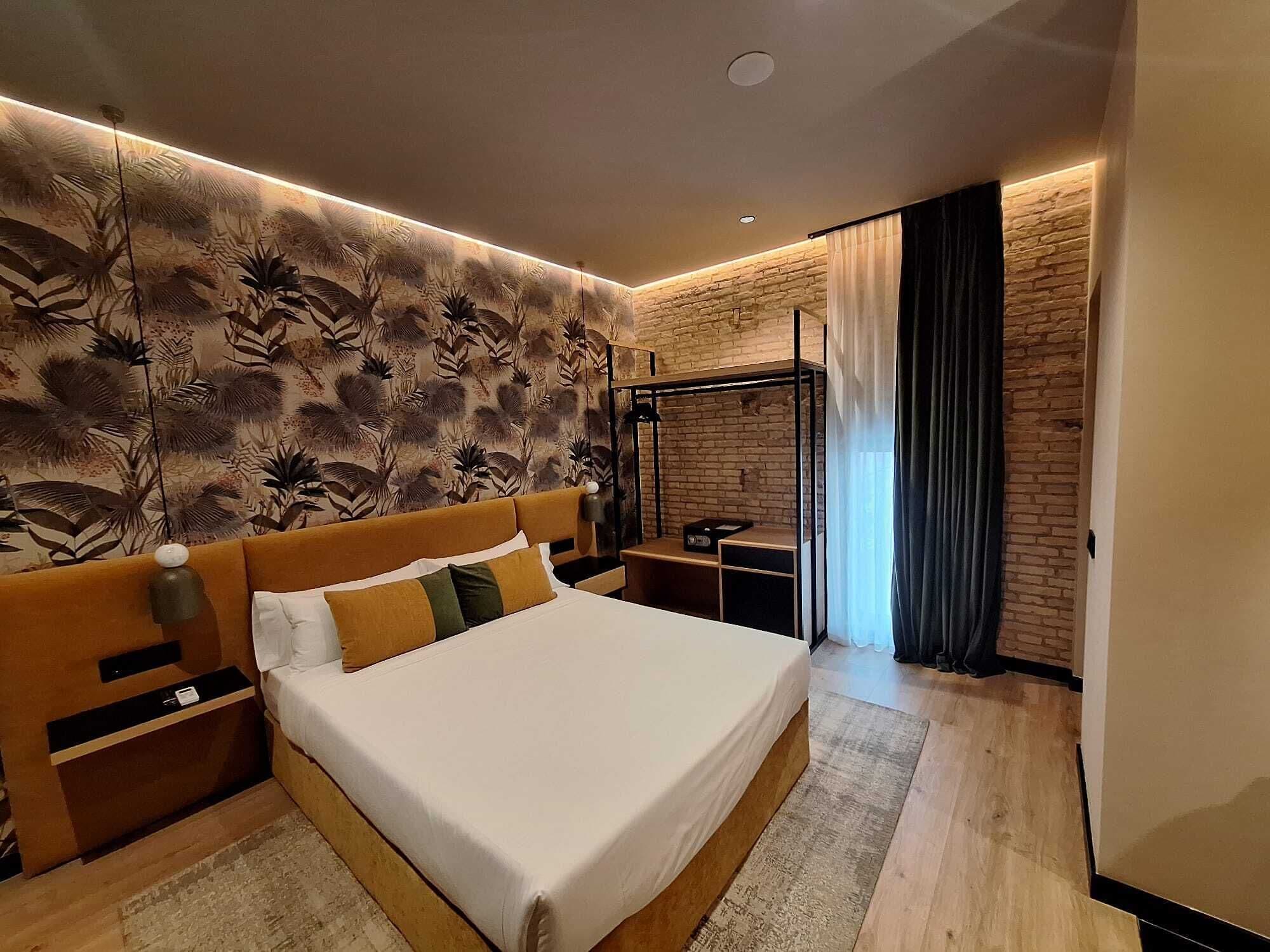 A modern bedroom with a large bed, a brick accent wall, and a ceiling light fixture.