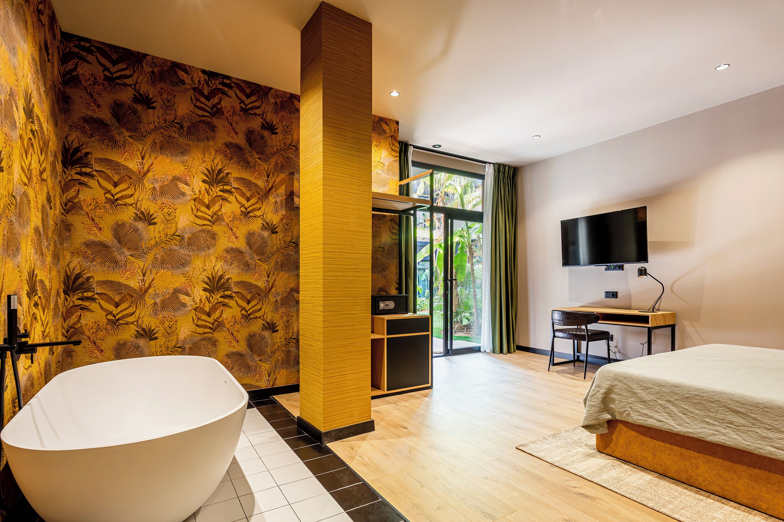 A modern hotel room with a large bathtub, a desk with a chair, a bed, and a TV.