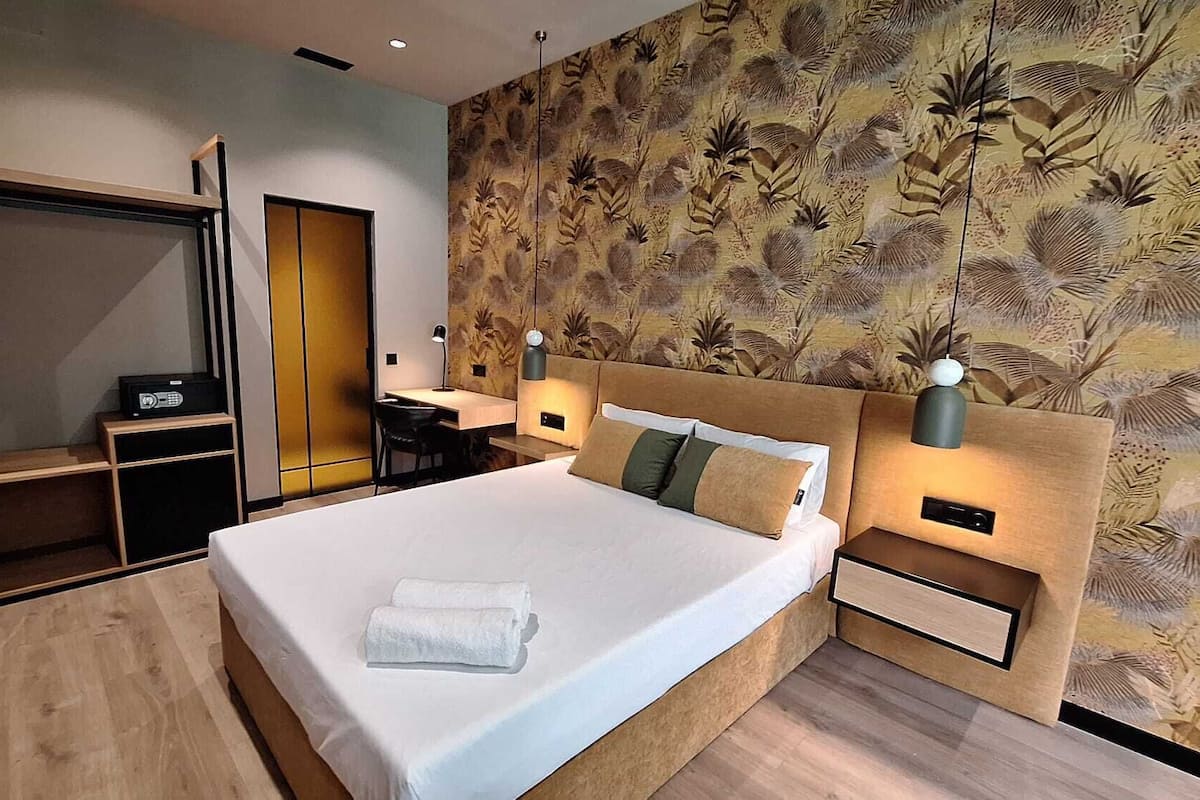Una habitación de hotel moderna con una cama grande, un escritorio y un armario.