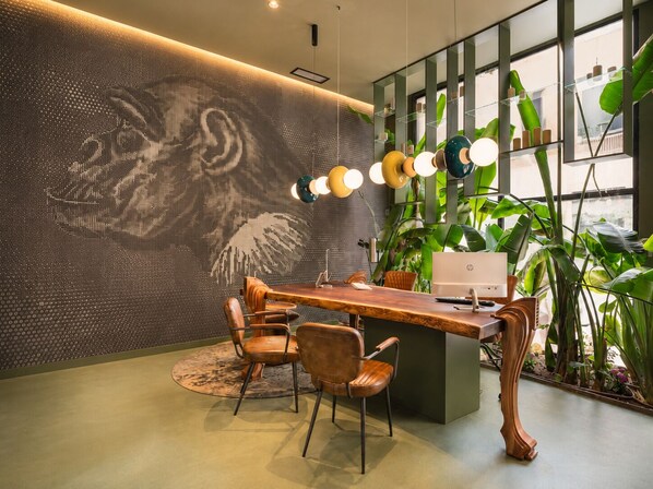 Un espace de bureau moderne avec un bureau en bois, des chaises, une grande plante et un mur orné d’un motif texturé.
