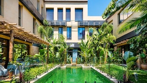 A modern building with a central pool, surrounded by lush greenery and a pergola. - Saman Boutique Hotel (Valencia)