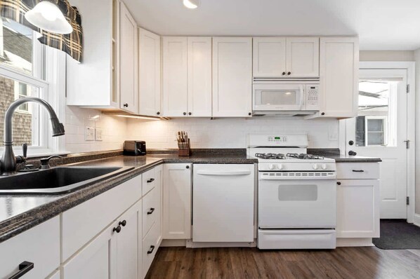 A kitchen with white cabinets, a microwave, a stove, and a dishwasher. - Wright by the Sea For 10! (York Beach)
