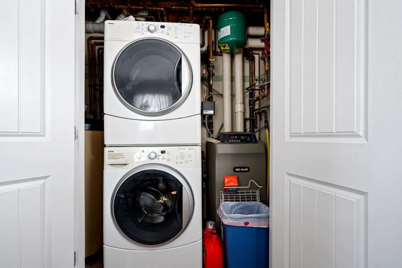 A compact laundry room with two stacked washing machines and a water heater.